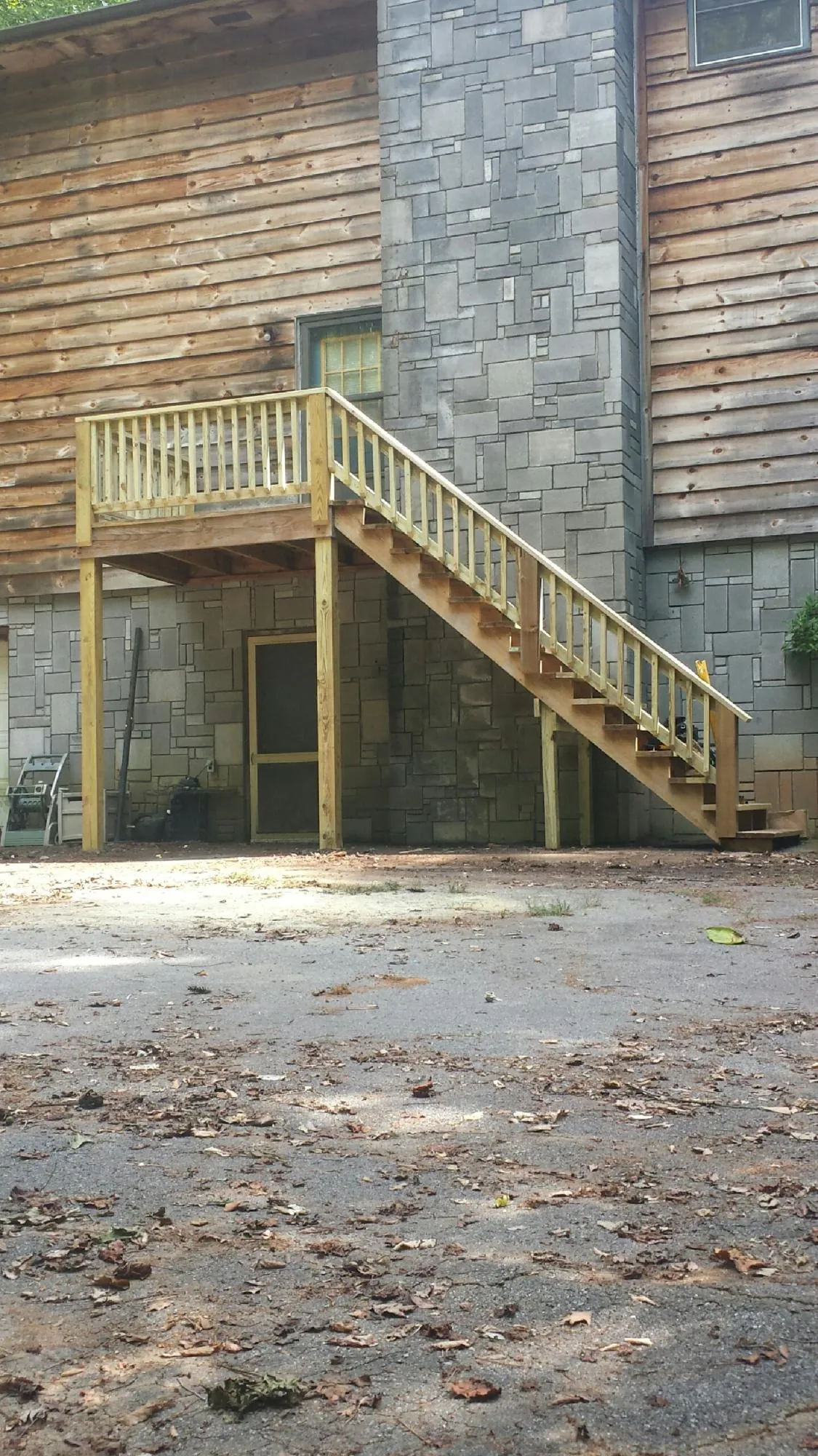 New pressure treated deck and stair landing on a log home in Liberty