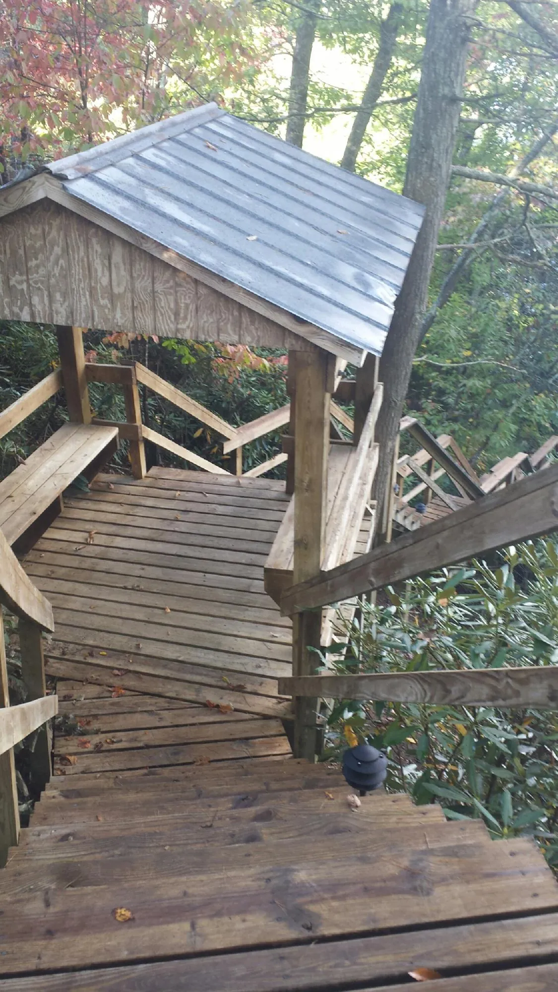 Metal roofed shelter over wooden steps on a wooded walkway — Skylight Repair & Installation work by our crew in Liberty